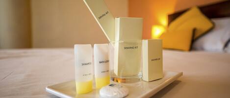 A tray with a shaving kit, shampoo, and bath lotion on a bed.