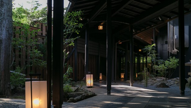 Ein traditionelles japanisches Gebäude mit überdachtem Gang, Laternen und einem Kiesweg.