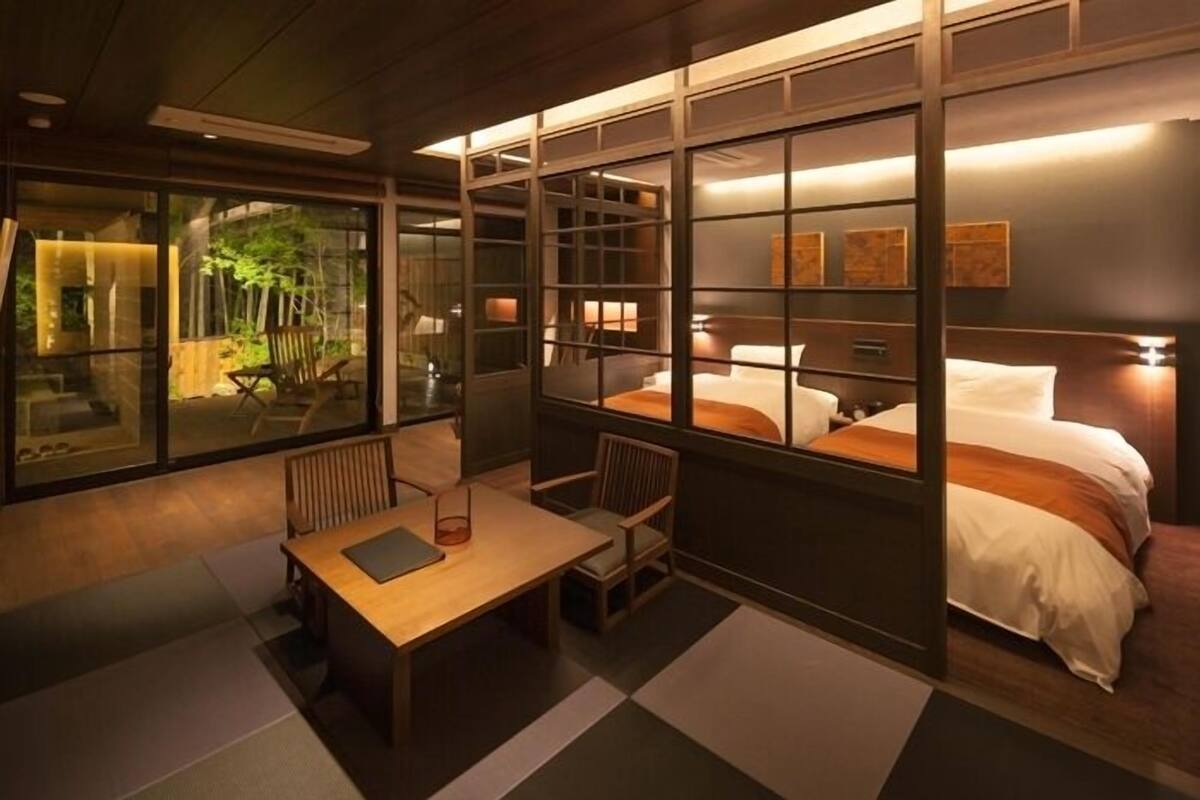 Ein modernes Hotelzimmer mit großem Fenster, einem Bett, einem Schreibtisch und einem Stuhl.