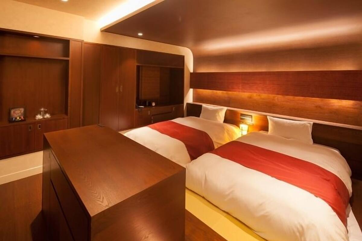 Ein Hotelzimmer mit einem großen Bett, einem Holztisch und integrierten Regalen.