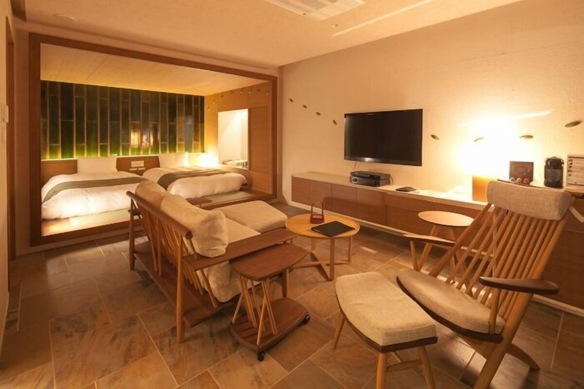 Ein modernes Hotelzimmer mit Bett, Sofa, Fernseher und einem kleinen Tisch.
