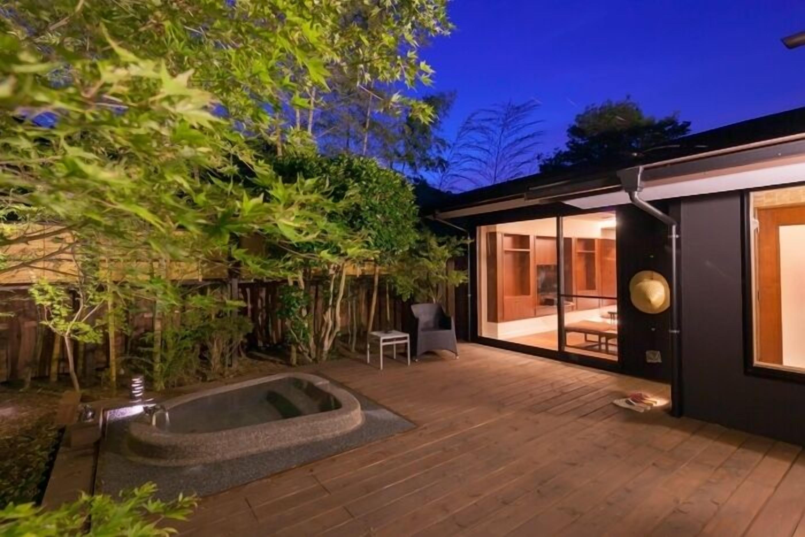 Ein modernes Haus mit einer Holterrasse, einem Whirlpool und einem gläsernen Essbereich.