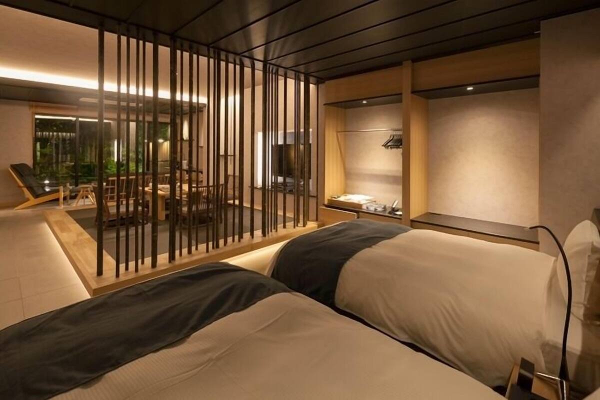 Ein modernes Hotelzimmer mit einem großen Bett, einer Sitzecke mit Sofa und Sesseln sowie Blick ins Freie.