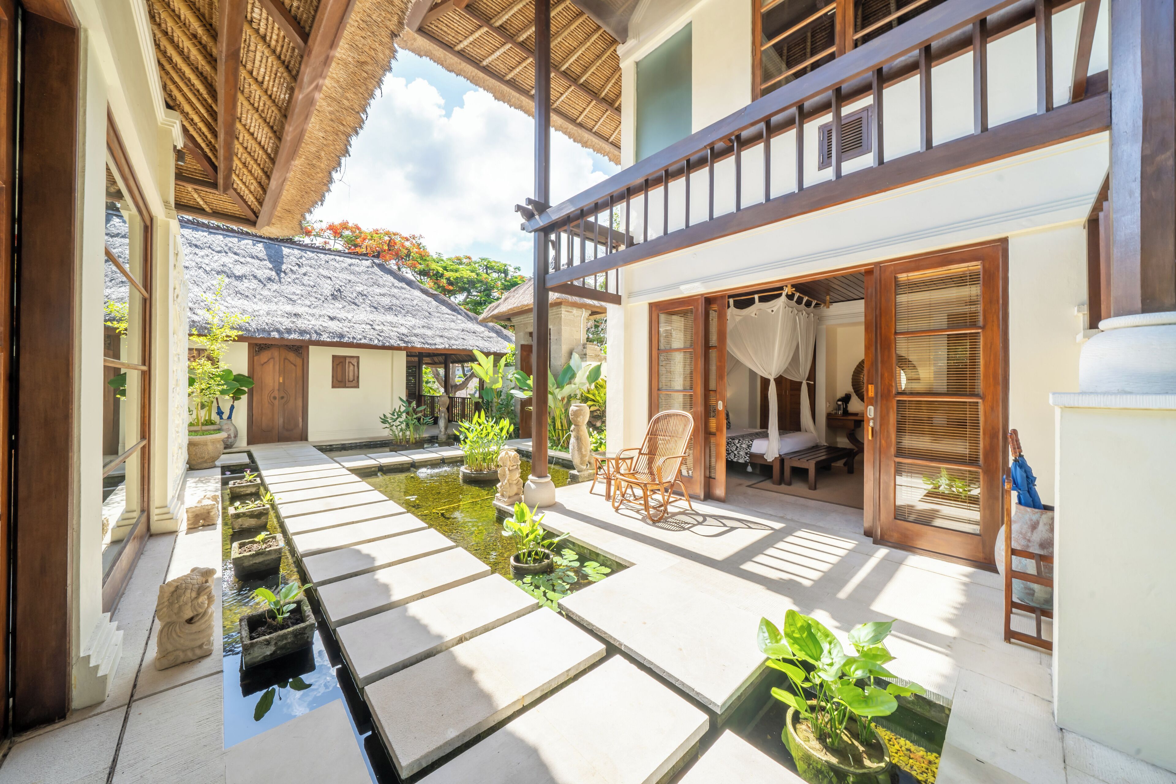 A traditional Japanese-style building with a thatched roof, a koi pond, and a wooden veranda.