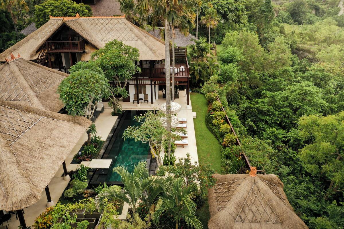 Ein Resort mit strohgedeckten Villen, einem Swimmingpool und üppiger Vegetation.