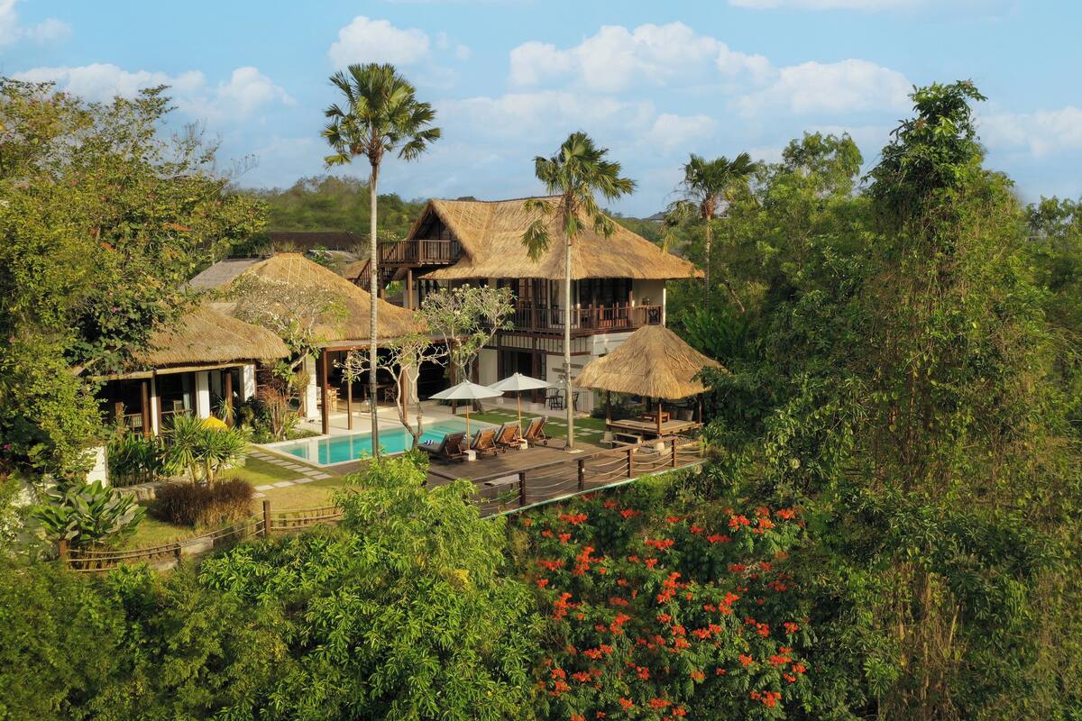 Ein Resort mit Pool, strohgedeckten Gebäuden und üppiger Bepflanzung.