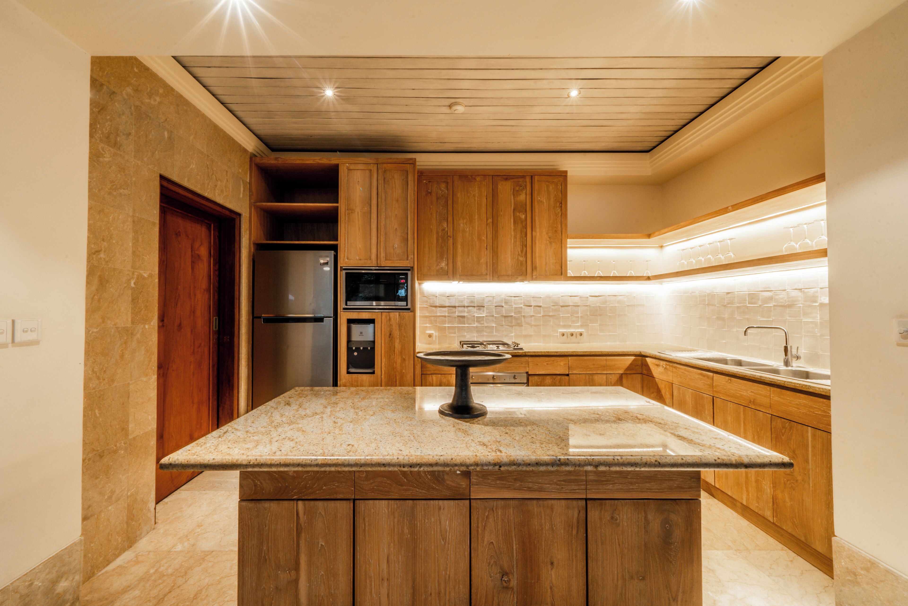 Une cuisine moderne avec des meubles en bois, un plan de travail en granit et des appareils électroménagers intégrés.