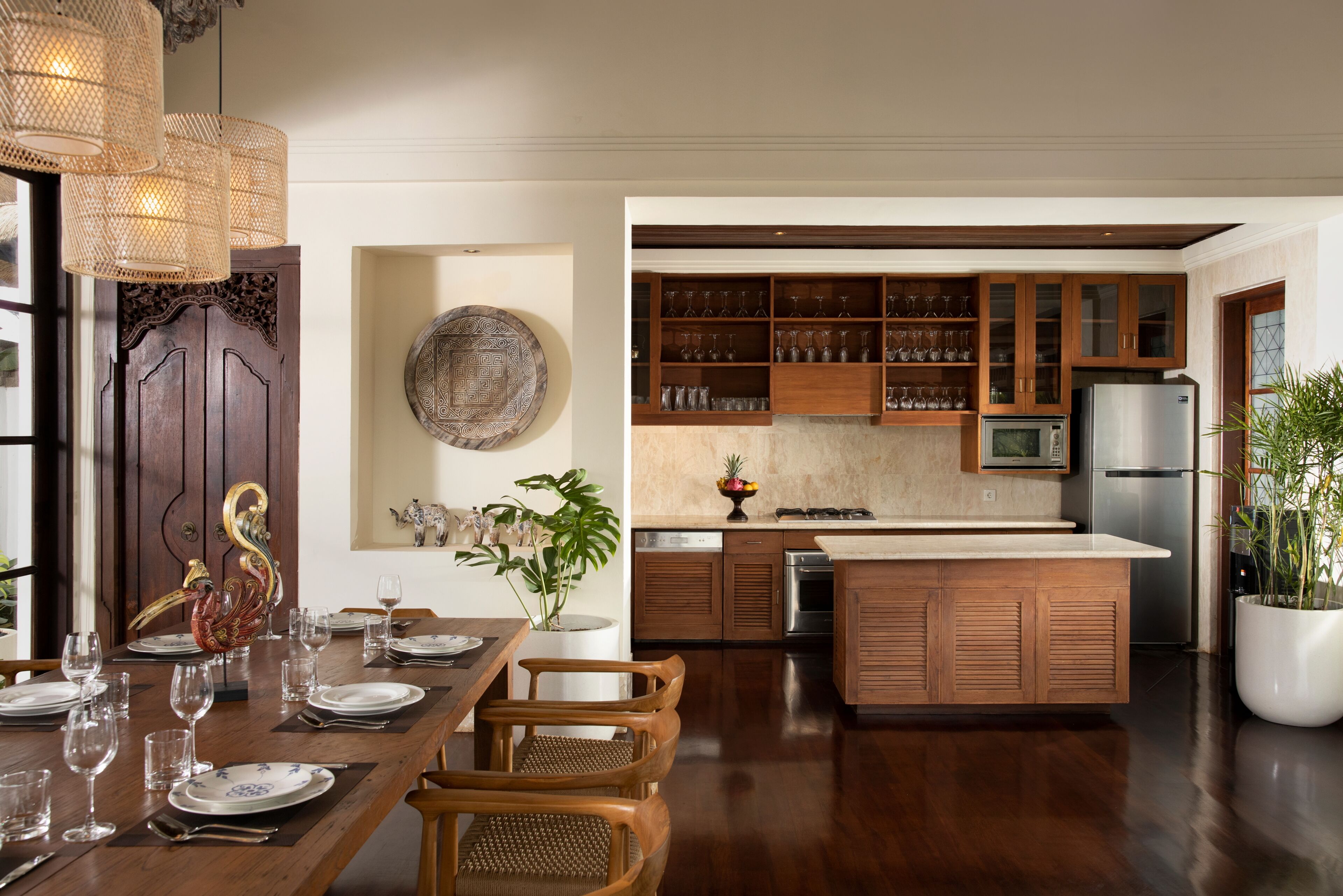 Una cocina moderna con armarios de madera, una isla central y un comedor con una mesa dispuesta para seis personas.