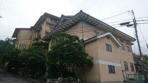 Um edifício de vários andares com estilo arquitetônico tradicional, apresentando um telhado inclinado e várias janelas.