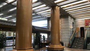 Un hall d’entrée spacieux, doté de grandes colonnes, d’un escalier et d’un sol carrelé.