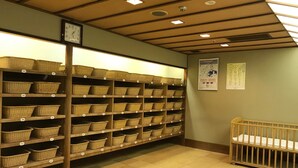 Une pièce avec des étagères en bois remplies de paniers en osier, un berceau en bois et une horloge au mur.