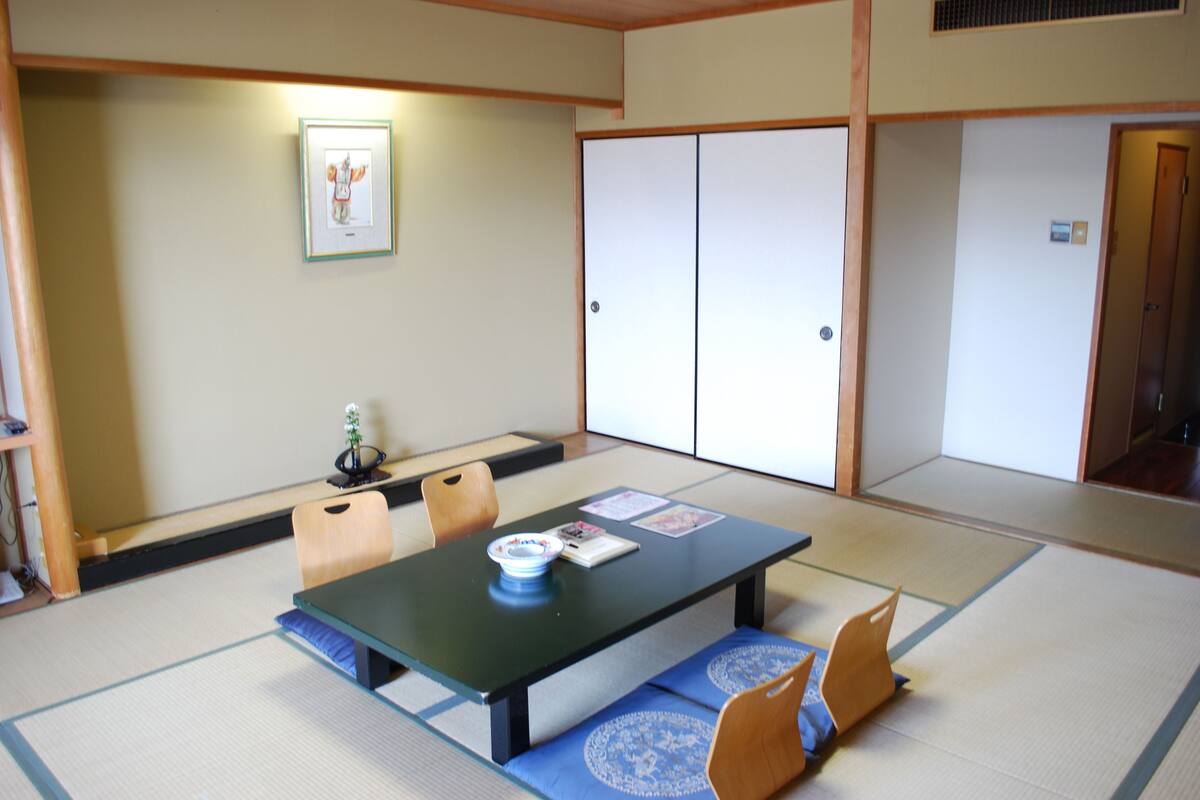 Une pièce de style japonais traditionnel, avec un sol recouvert de tatamis, une table basse et une porte coulissante.