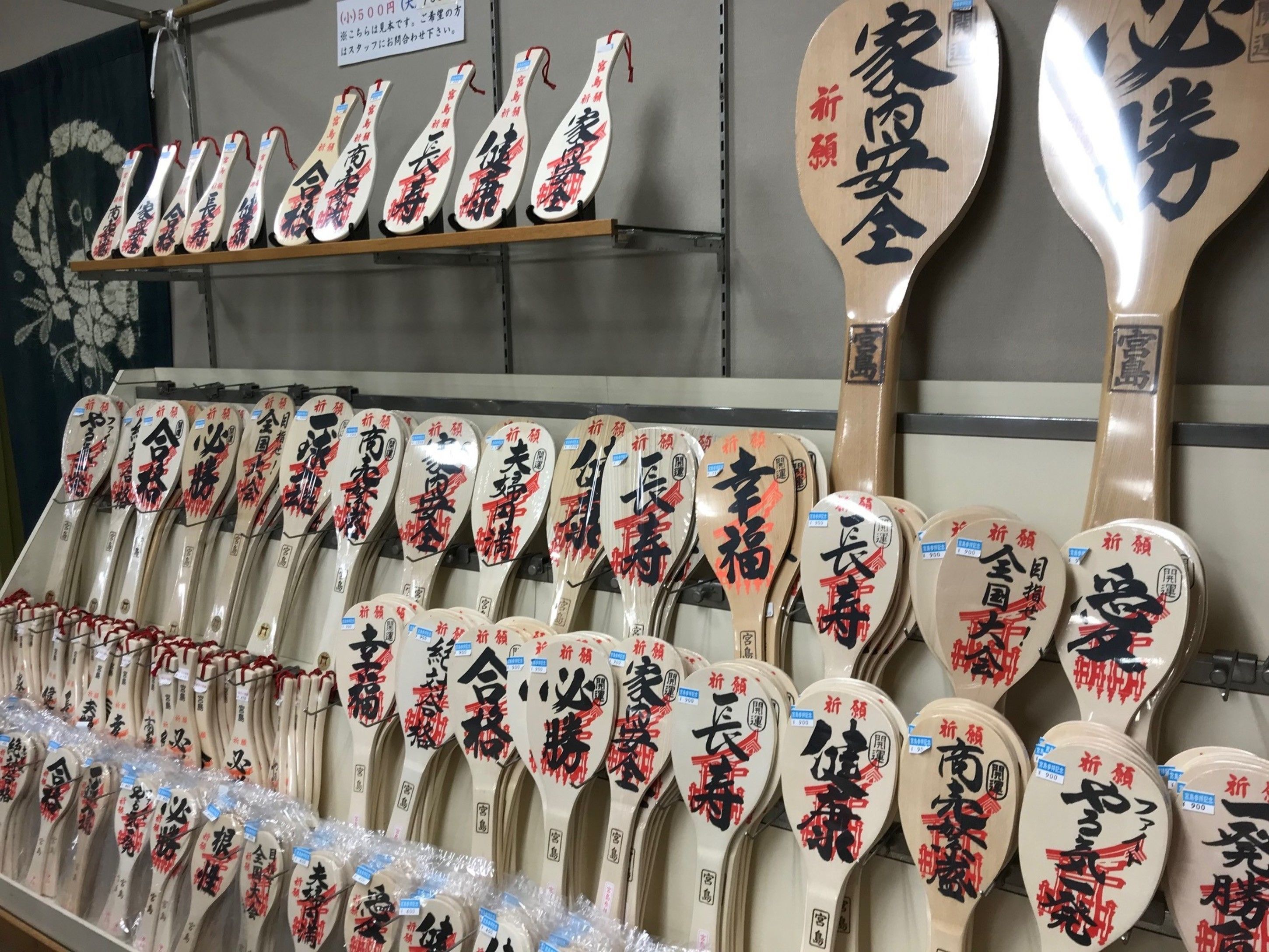 A display of wooden ladles with Japanese calligraphy, likely for sale.