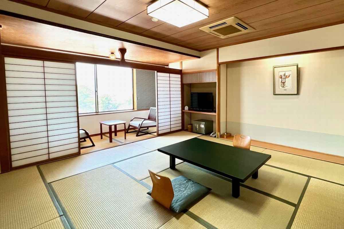A tatami mat room with a tatami mat table, a television, and a framed picture on the wall.