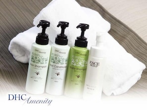 Four bottles of DHC Amenity hair care products on a white towel. - Hotel AreaOne Kagoshima (Kagoshima)