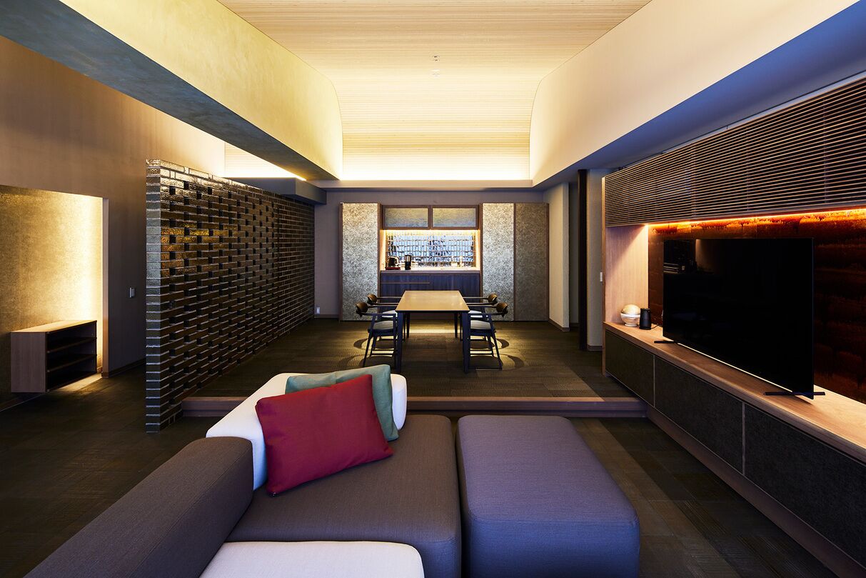 A modern living room with a sofa, a TV, a fireplace, and a dining area.