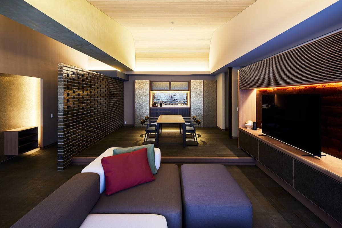 A modern living room with a sofa, a TV, a fireplace, and a dining area.