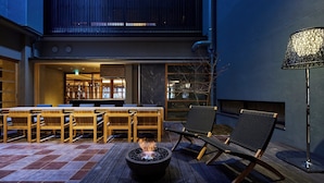 An outdoor patio with a fire pit, wooden chairs, and a table. - Itsukushima Iroha  (Hatsukaichi)