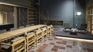 A modern indoor space with a long wooden table and chairs, a tiled floor, and a fireplace. - Itsukushima Iroha  (Hatsukaichi)