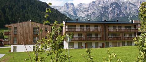 A hotel with a wooden facade and balconies overlooking a mountainous landscape.