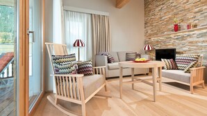 Ein modernes Wohnzimmer mit Holzboden, Steinwand, einer Couch, einem Schaukelstuhl und einem Fernseher.