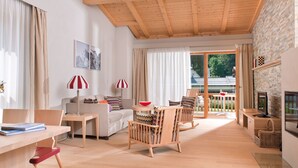 Ein modernes Wohnzimmer mit Holzbalkendecke, einer Couch, einem Esstisch und einem Fernseher.