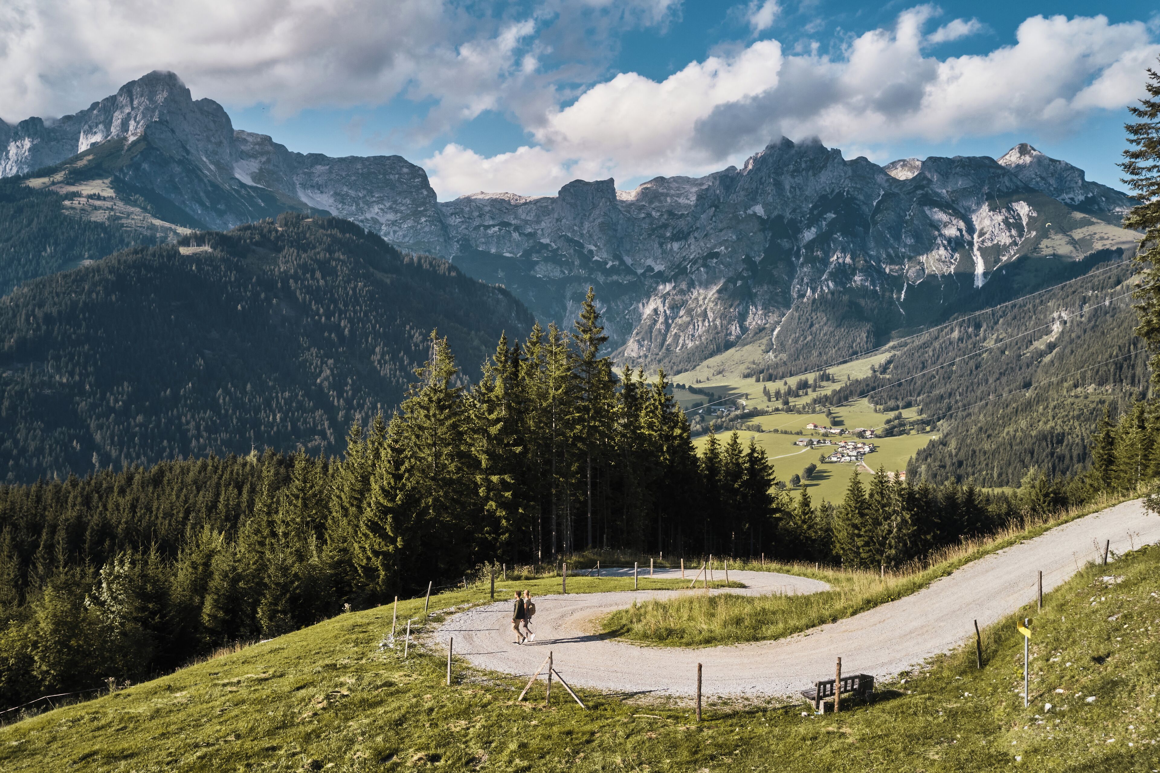A mountain road with a clear view of a valley and distant mountains.