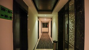 Un pasillo de hotel con señales de dirección, un cubo de basura y una alfombra estampada.