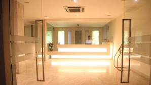 Un área de recepción con suelo de mármol, mostrador de recepción y una escalera.