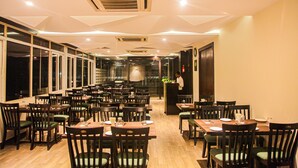 Un restaurante espacioso con numerosas mesas y sillas, amplias ventanas y un diseño de techo moderno.
