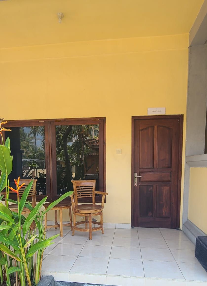 Un espacio al aire libre cubierto con una silla y una mesa de madera, una puerta de madera y un cartel sobre la puerta.