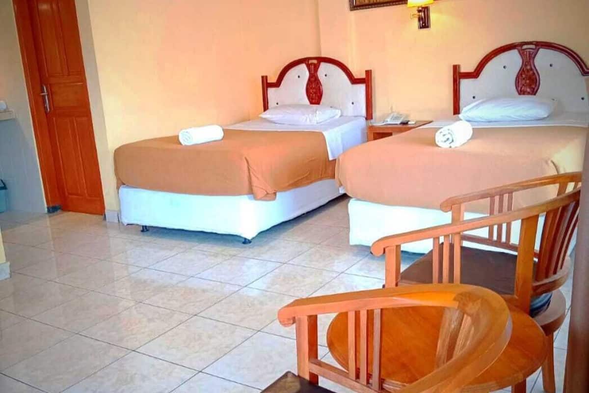 A hotel room with two beds, a dining table, and chairs.