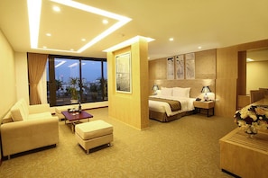 Habitación de hotel con cama, sofá, escritorio y vistas a la ciudad.