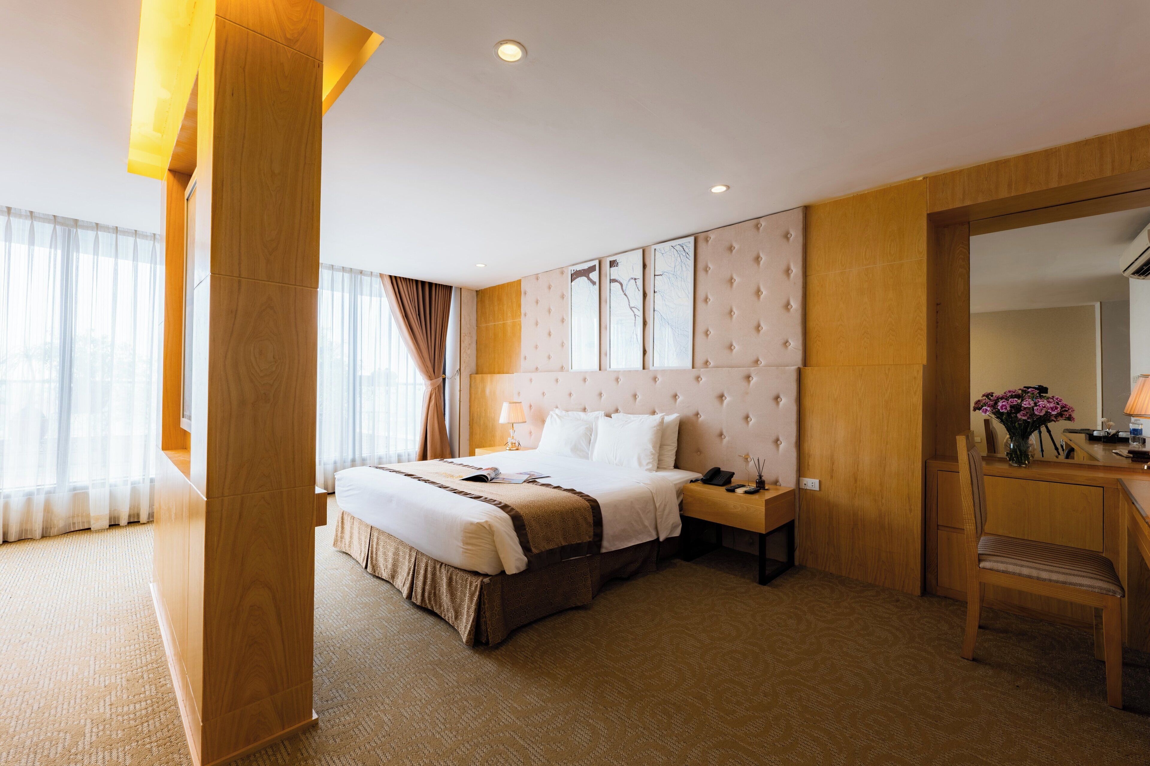 A hotel room with a large bed, bedside tables, a desk, and a chair.