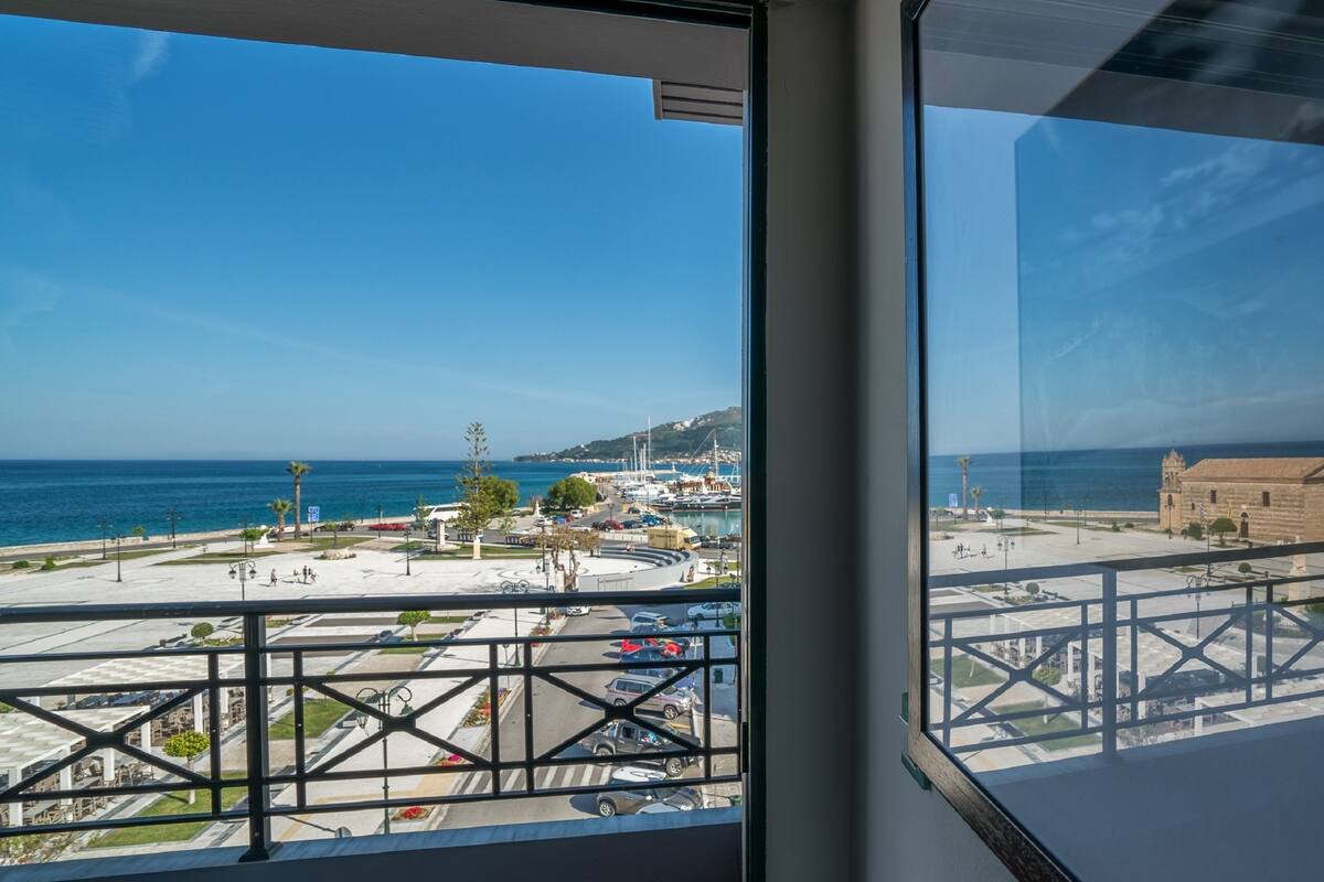 A balcony with a view of a marina, boats, and a coastal town.
