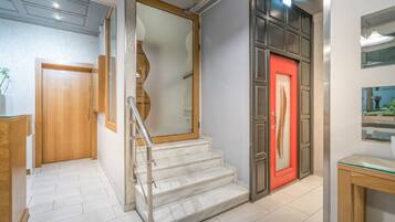 Ein modernes Interieur mit einer Treppe, einer Holztür und einer roter Tür.
