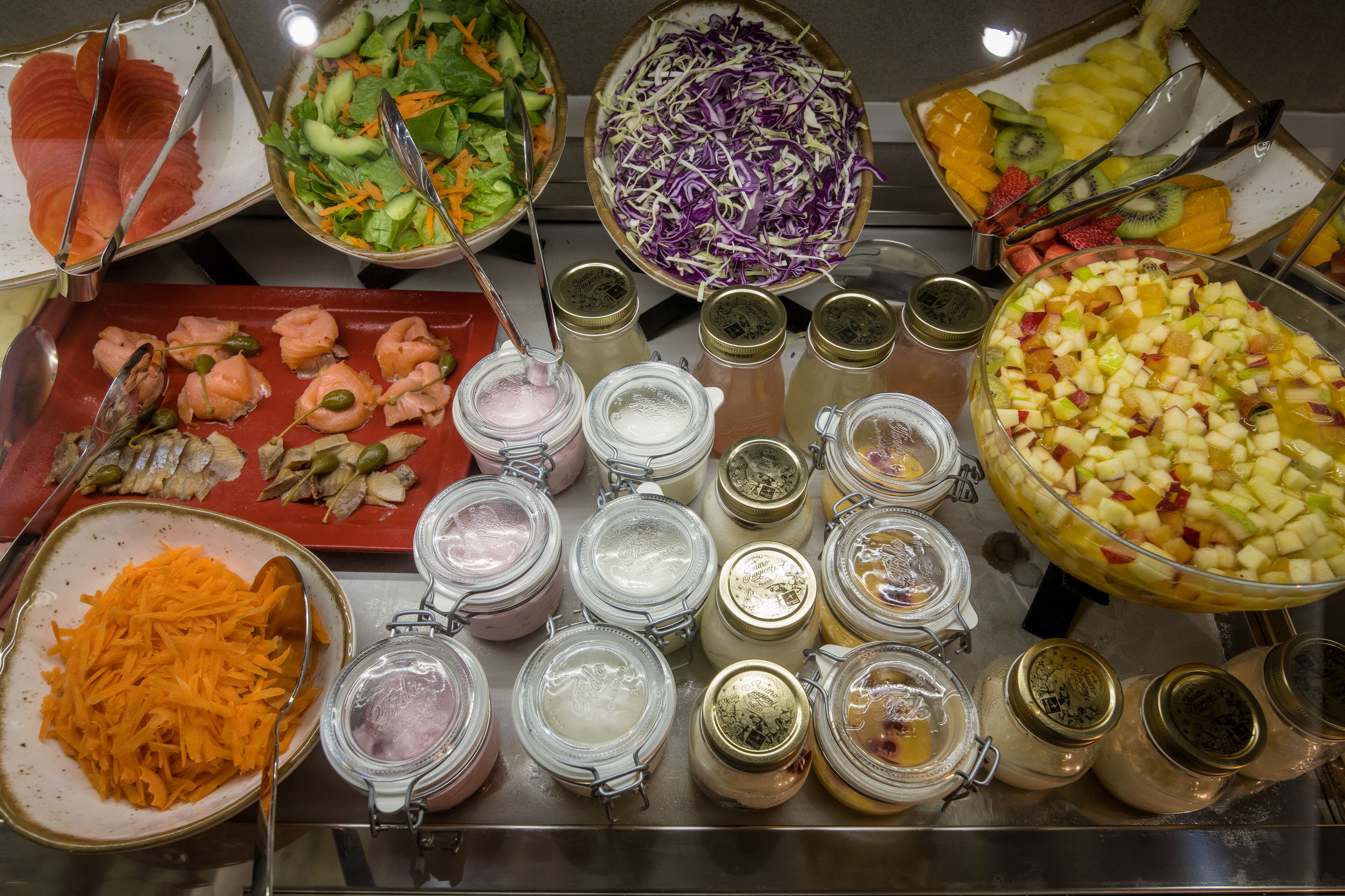 A buffet with various food items including salmon, salads, and fruit.