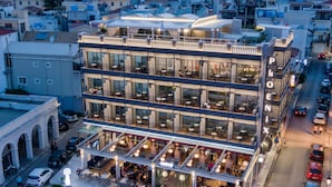 A multi-story hotel with outdoor seating areas and a rooftop terrace.