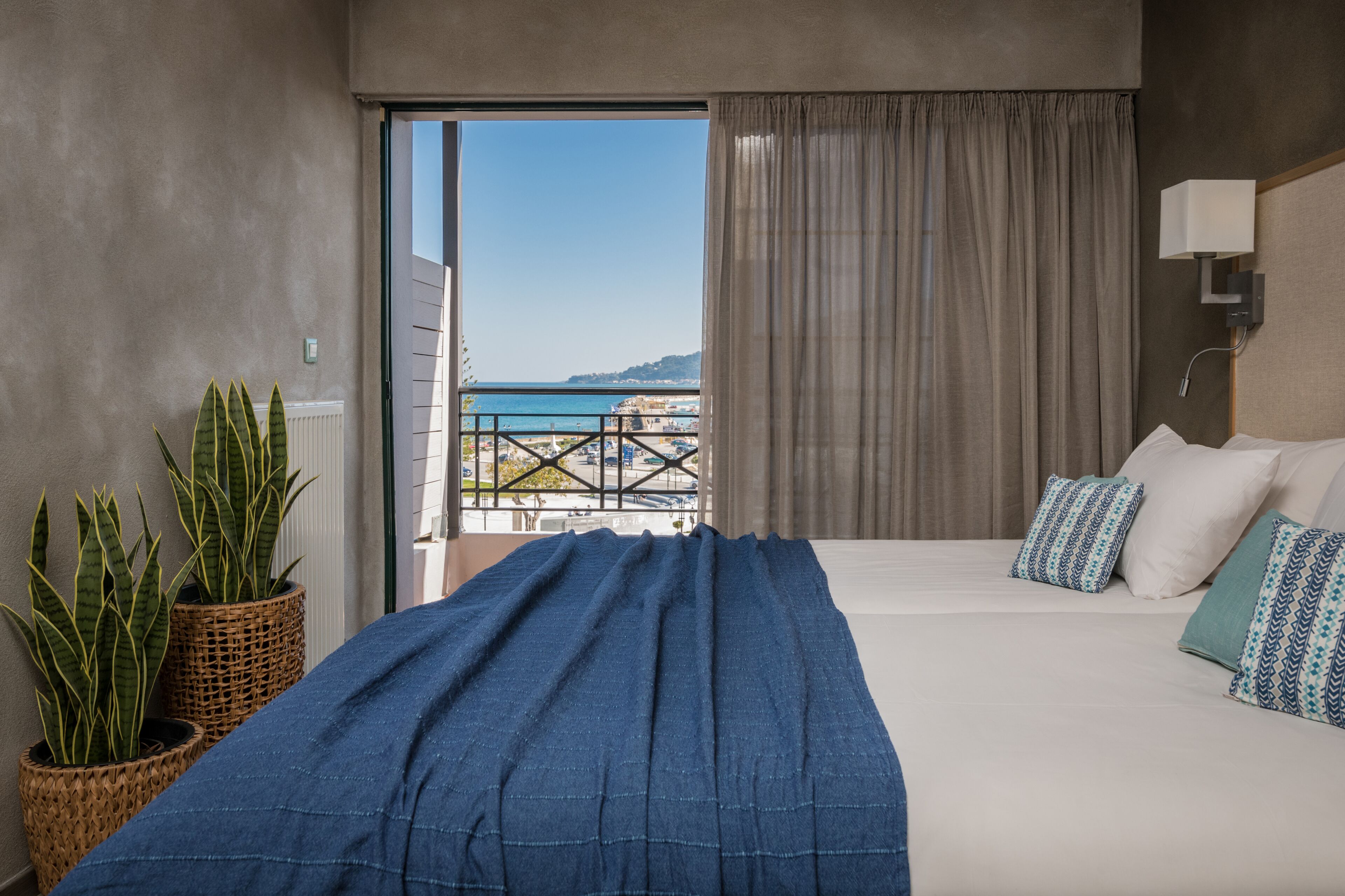 Habitación de hotel con cama, vista al mar y balcón.