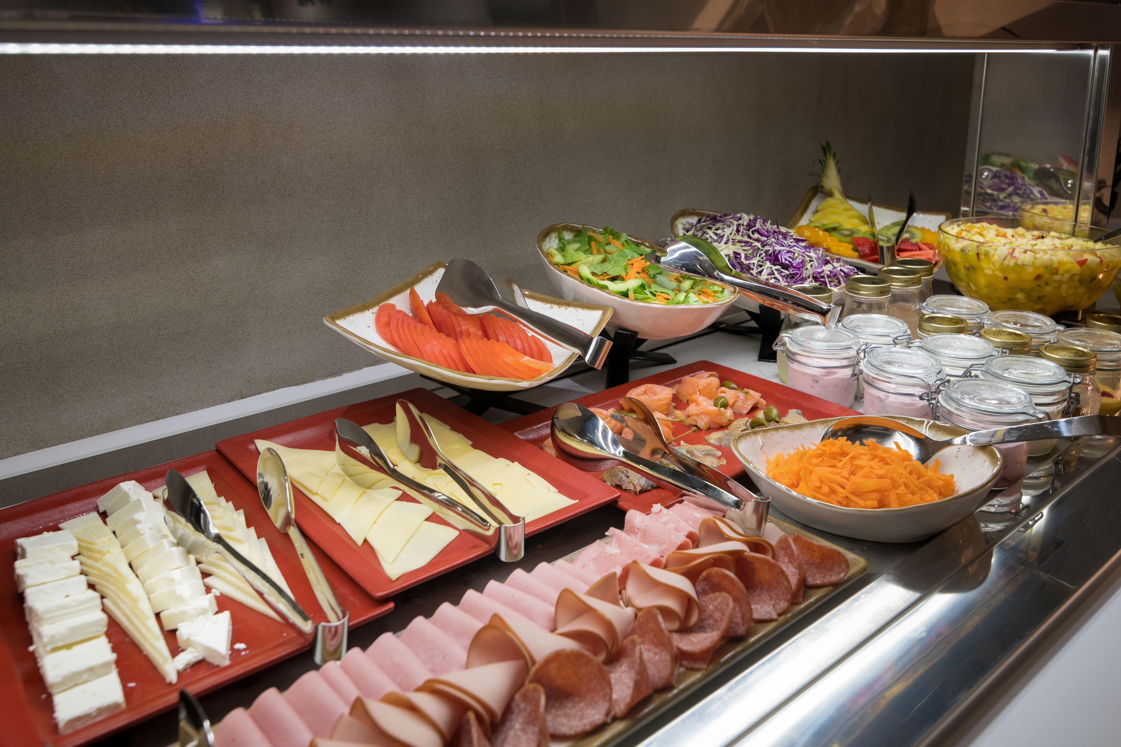 A buffet with various food items including cheese, ham, and salads.
