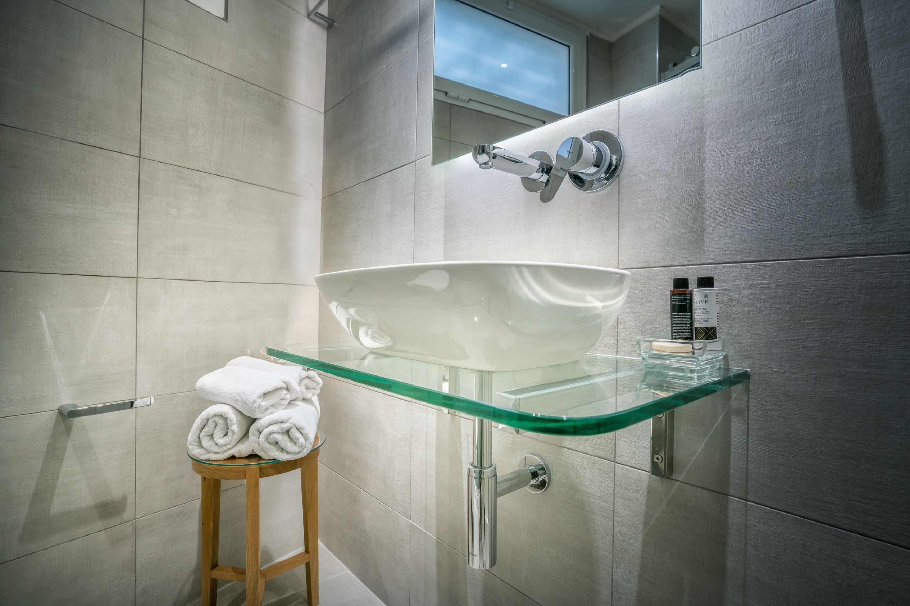 Ein modernes Badezimmer mit einem Waschbecken aus Glas, einer Handtuchstange und einem Spiegel.