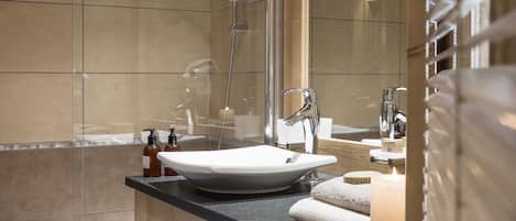 A modern bathroom with a wooden vanity, a large mirror, a bathtub, and a sink.