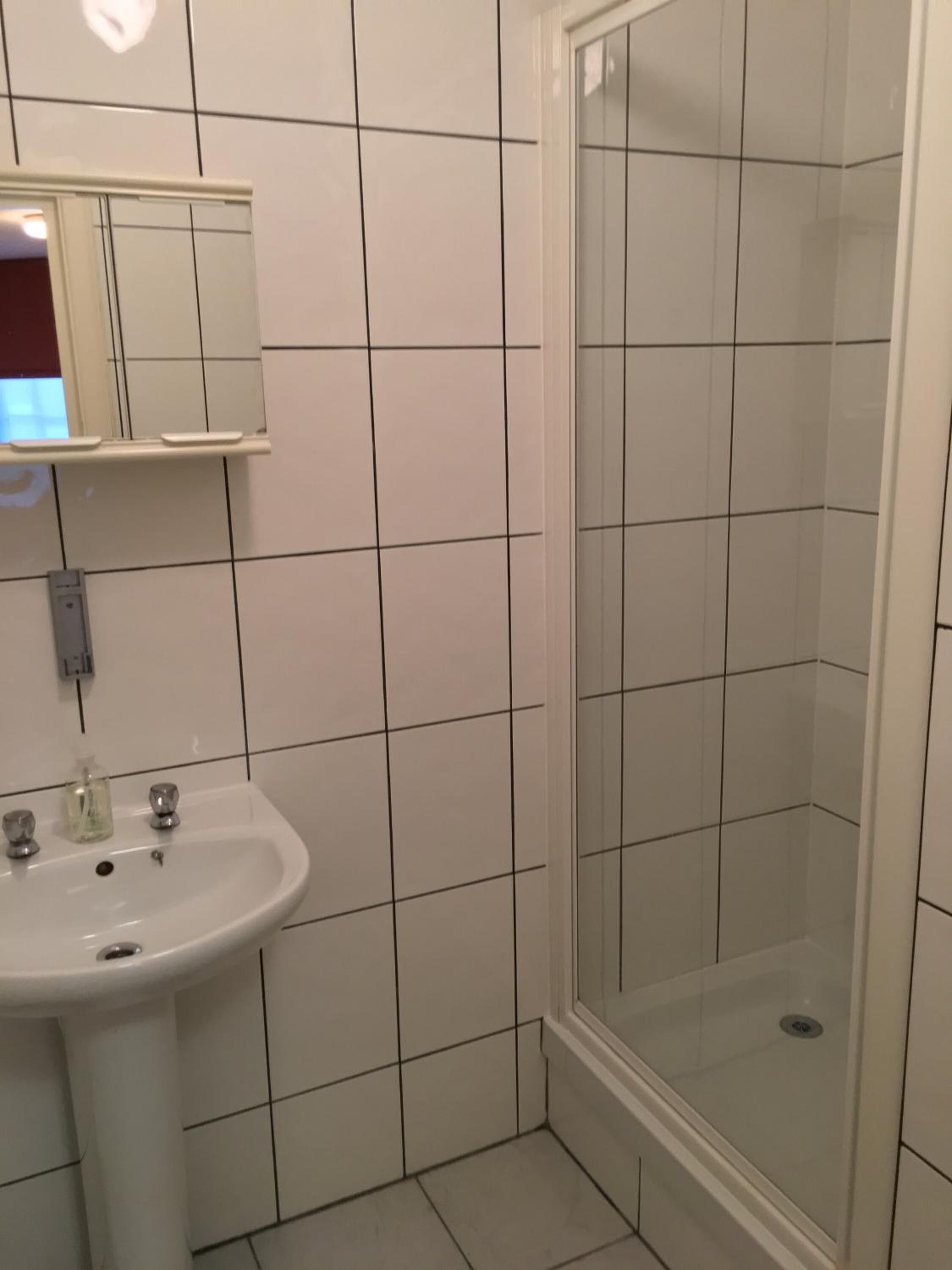 Un bagno con lavandino bianco, specchio e doccia.
