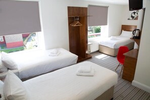 A hotel room with two single beds, a desk with a chair, a TV, and a view of the outside. - Chelsea Guest House (London)
