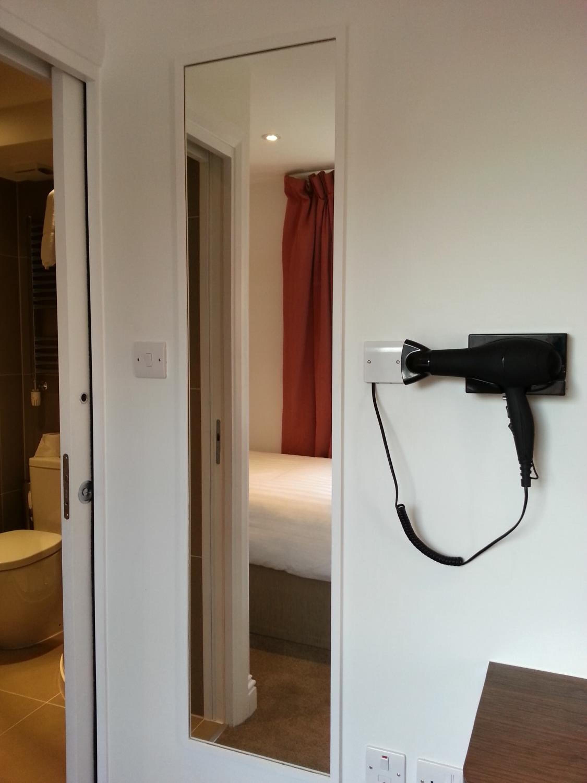 Ein Zimmer mit einem Bett, einer Dusche und einem an der Wand befestigten Föhn.