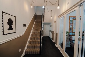A staircase with striped carpet, a wall-mounted silhouette, and a door leading to a room with a map. - Chelsea Guest House (London)