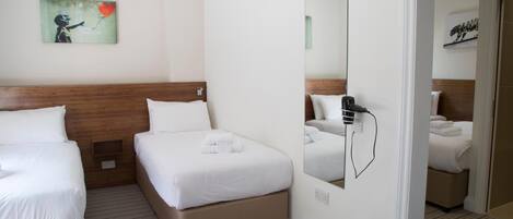 A hotel room with two beds, a large mirror, and a painting on the wall.