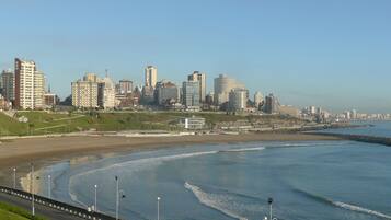 A coastal cityscape with a beach, high-rise buildings, and a promenade.