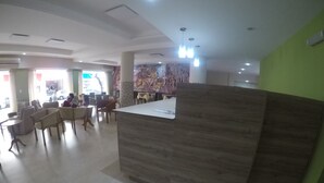 A reception area with a wooden reception desk, several chairs, and a tiled floor. - Hotel Catedral (Mar del Plata)