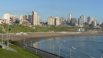 A coastal cityscape with a beach, high-rise buildings, and a promenade.